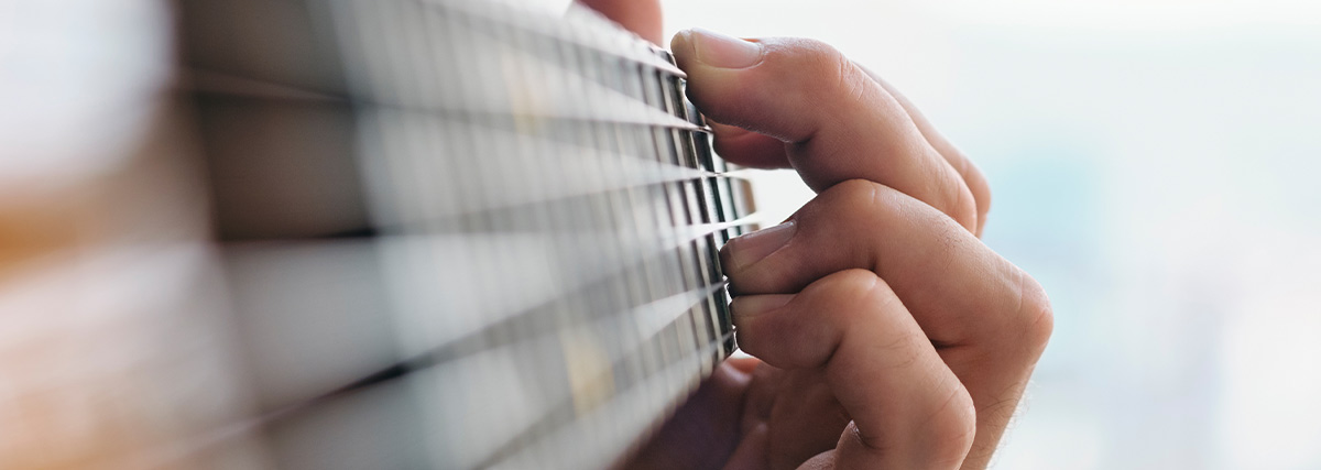 Man fingers pressing guitar strings