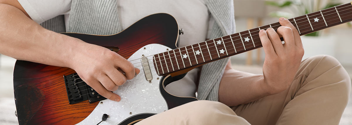Man hand holding electric guitar strings to play