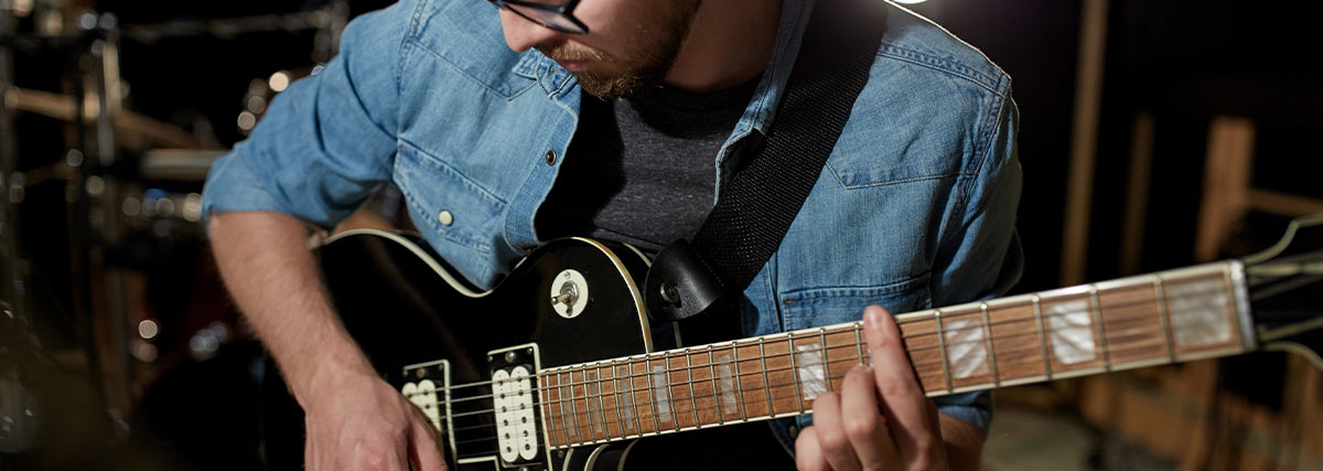 Man with glasses playing electric guitar