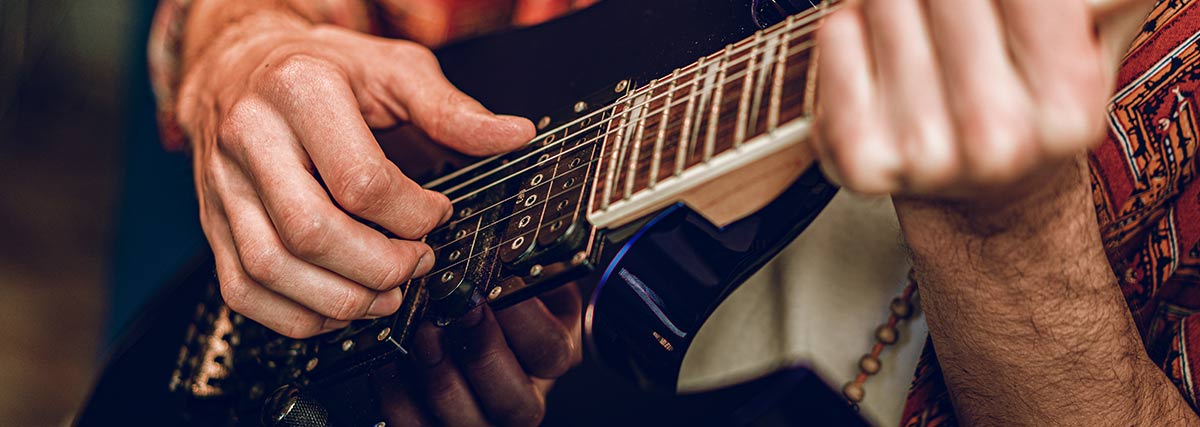 Focus on man right hand playing guitar