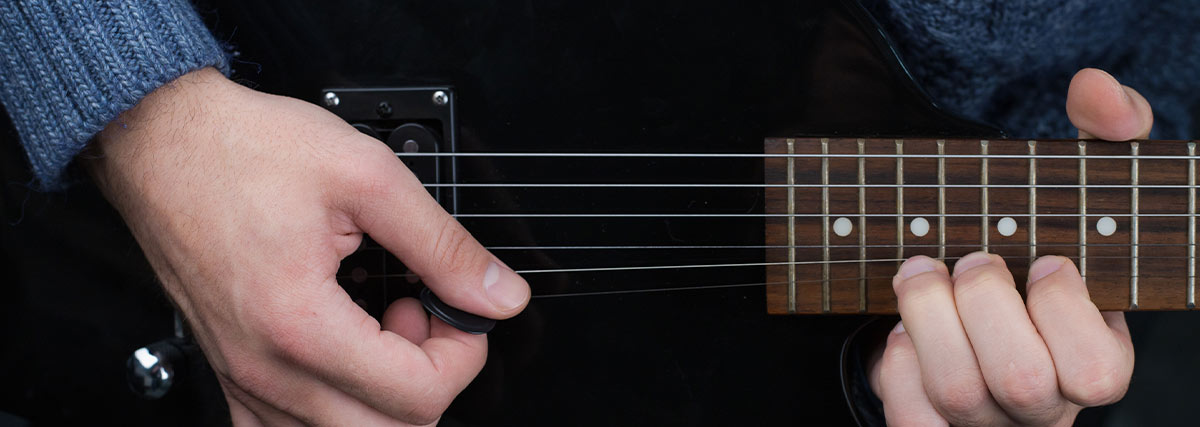 Hand of man with sweater playing guitar