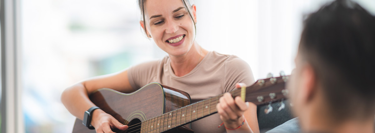 Woman smiling and playing guitar