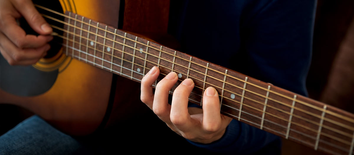 Male hands on the guitar fretboard