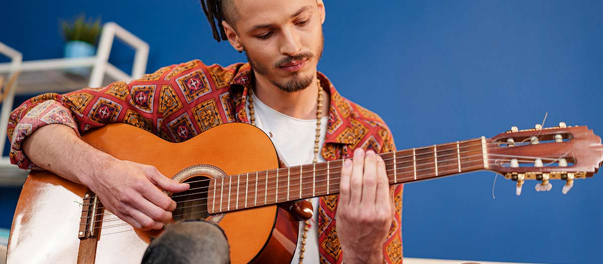 Man practising acoustic guitar chords during a relaxed guitar lesson at home