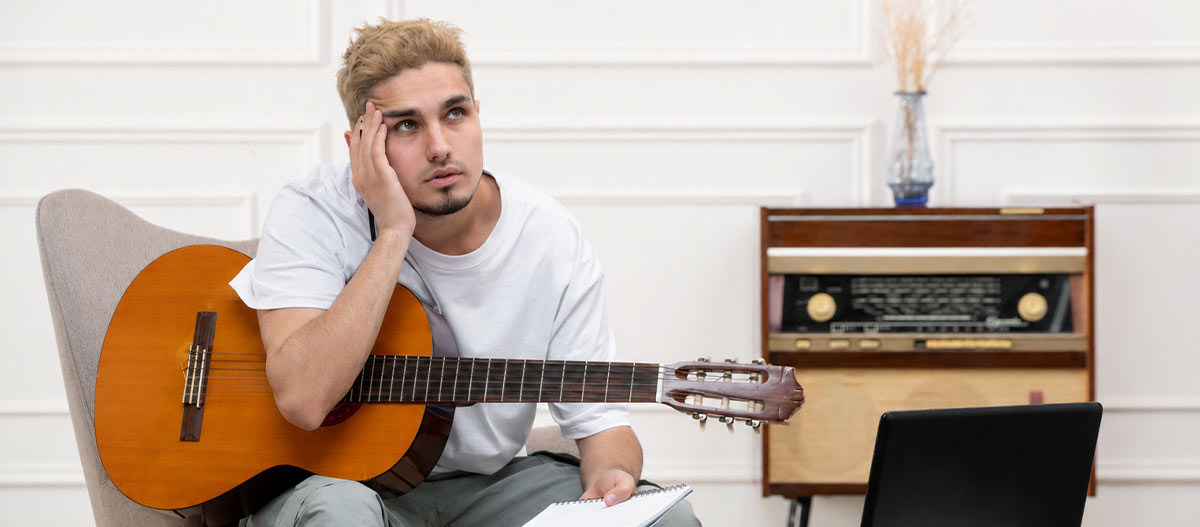 Adult guitarist thinking through a practice exercise while holding an acoustic guitar