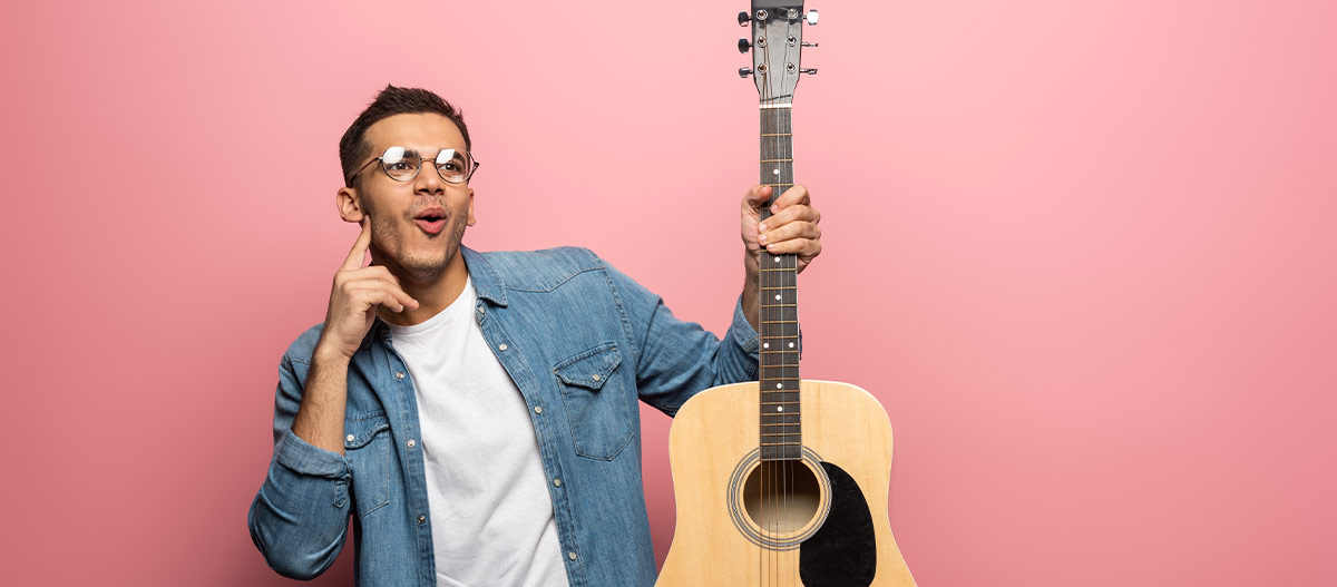 Beginner guitarist holding an acoustic guitar while learning what an octave is