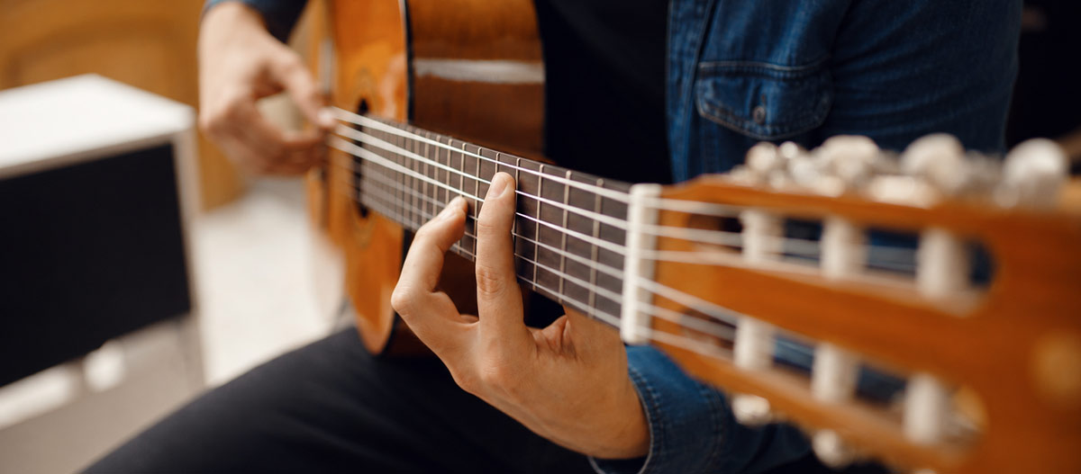 Close up of a classical guitarist practising octave finger positions on the fretboard