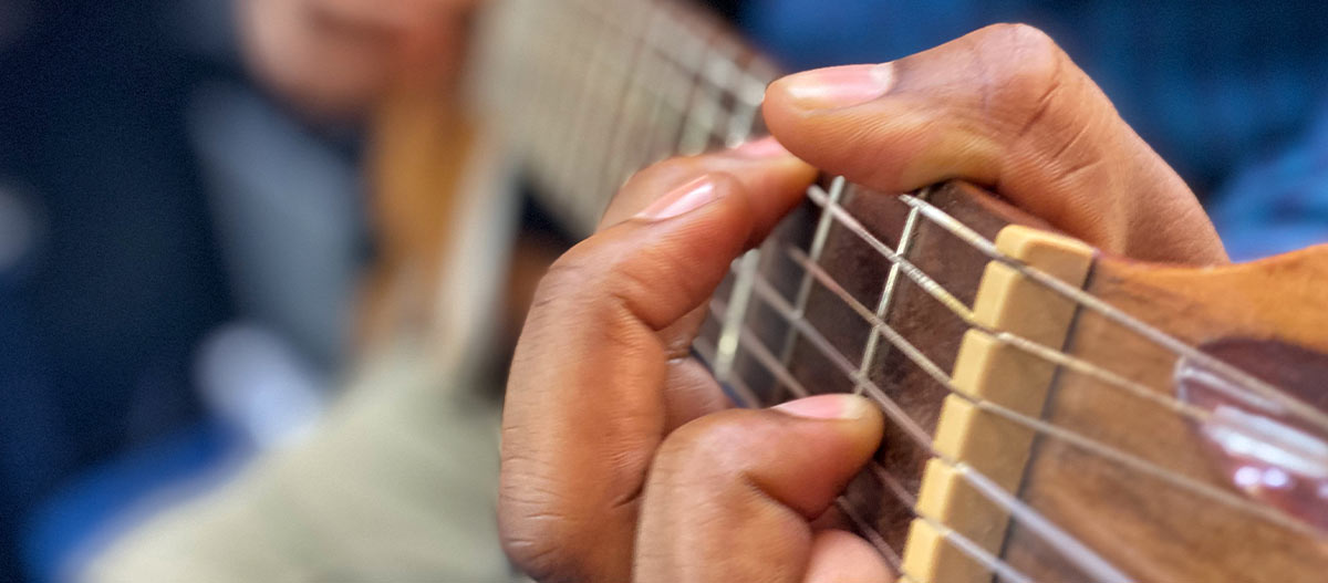 Professional guitarist playing octave notes on electric guitar fretboard
