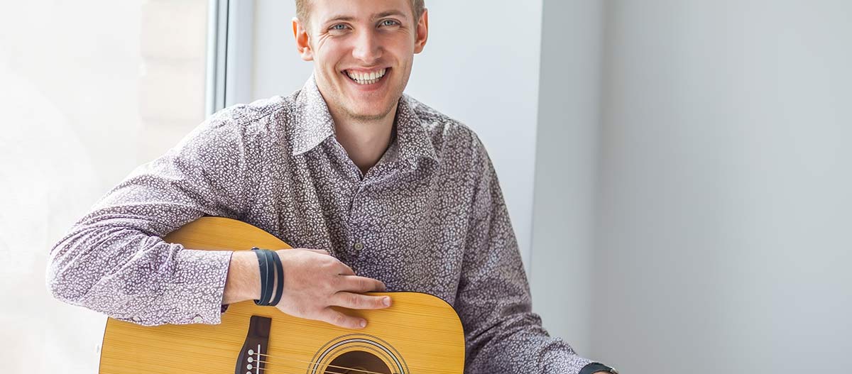 Smiling guitarist playing acoustic guitar during a relaxed music lesson