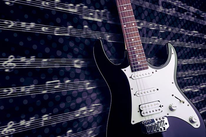 Electric guitar with musical notation representing essential guitar pieces every guitarist should learn