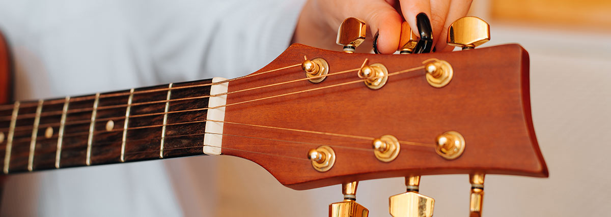 Hand of guitarist tuning and making adjustment